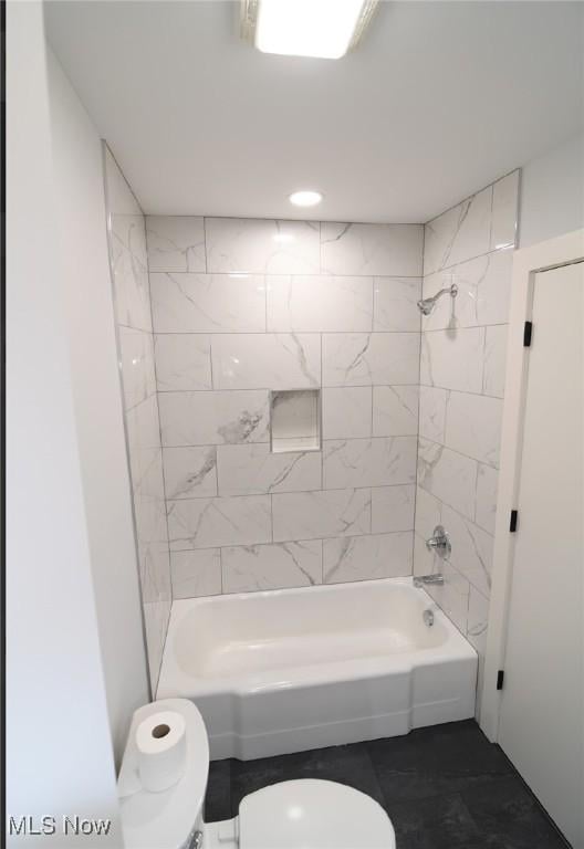 bathroom featuring tiled shower / bath combo and toilet