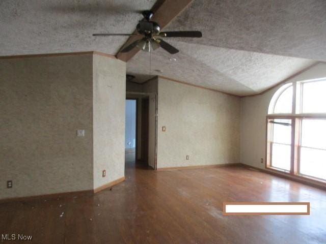 empty room with ceiling fan, vaulted ceiling, hardwood / wood-style floors, and a textured ceiling