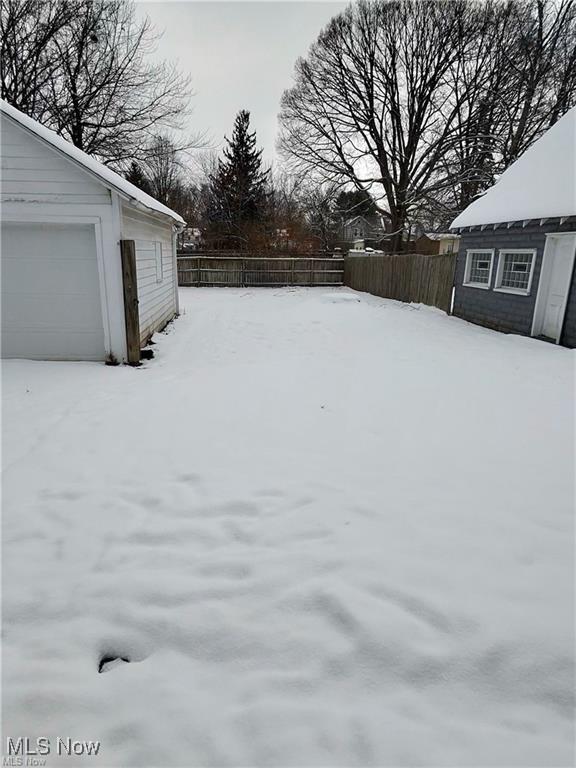 yard layered in snow with an outbuilding and a garage