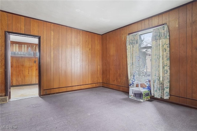 carpeted empty room featuring wooden walls