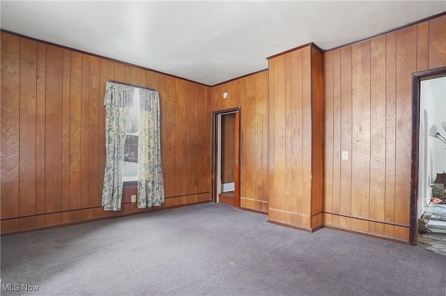 carpeted spare room with crown molding and wooden walls