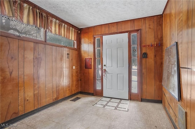 entrance foyer with a textured ceiling and wood walls