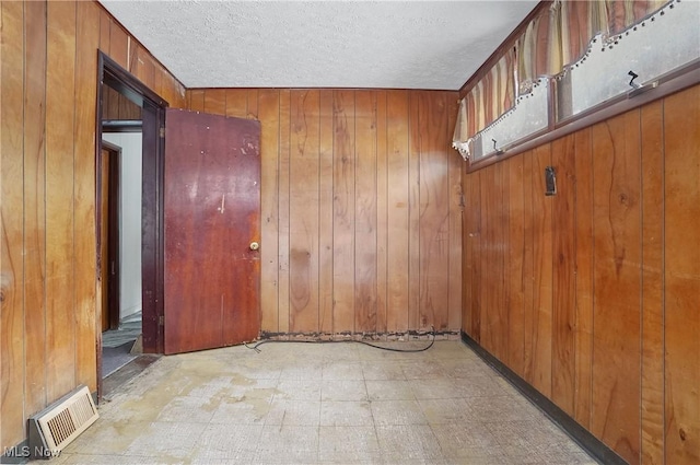 spare room featuring wooden walls and a textured ceiling