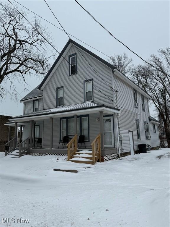 snow covered rear of property with covered porch