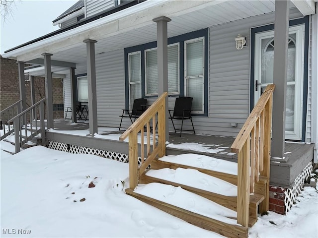 snow covered property entrance with a porch