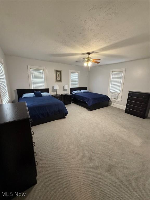 carpeted bedroom featuring ceiling fan and a textured ceiling