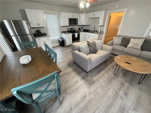 living room featuring sink, ceiling fan, and light wood-type flooring