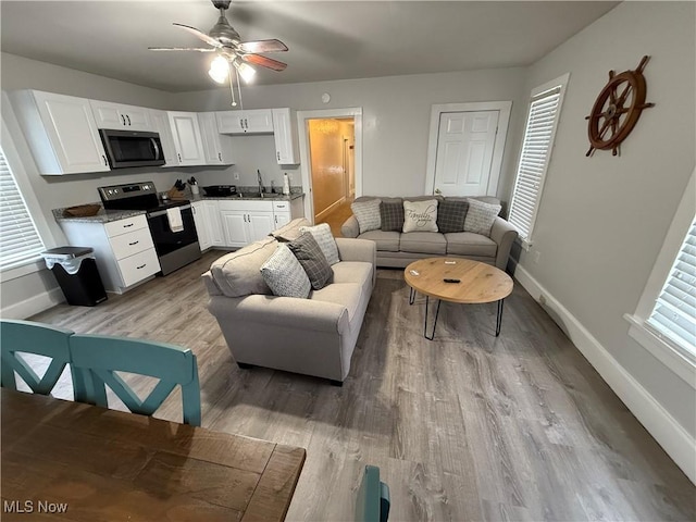 living room featuring sink, ceiling fan, and light hardwood / wood-style flooring