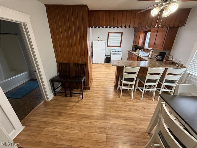 kitchen with white refrigerator, a kitchen breakfast bar, light wood-type flooring, and kitchen peninsula