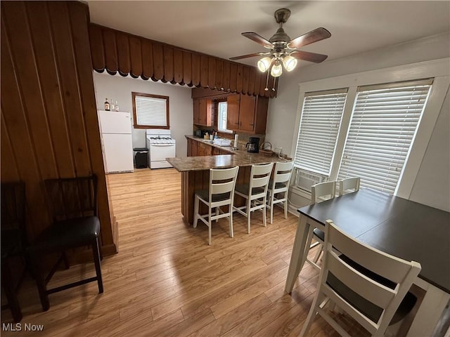 kitchen featuring backsplash, ceiling fan, kitchen peninsula, white appliances, and light hardwood / wood-style flooring