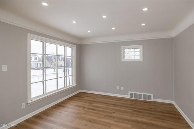 spare room with a wealth of natural light, ornamental molding, and hardwood / wood-style floors