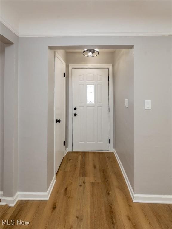 doorway featuring ornamental molding and light hardwood / wood-style flooring