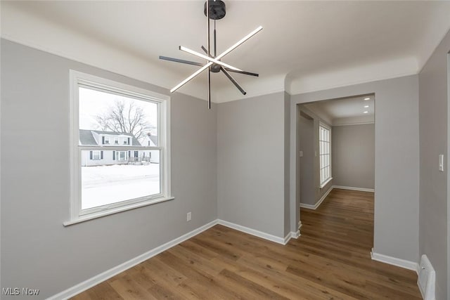 empty room with hardwood / wood-style flooring and a notable chandelier