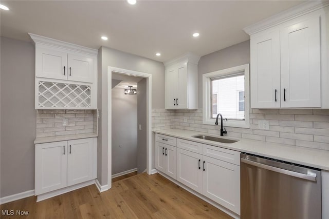 kitchen with white cabinetry, dishwasher, sink, backsplash, and light hardwood / wood-style floors