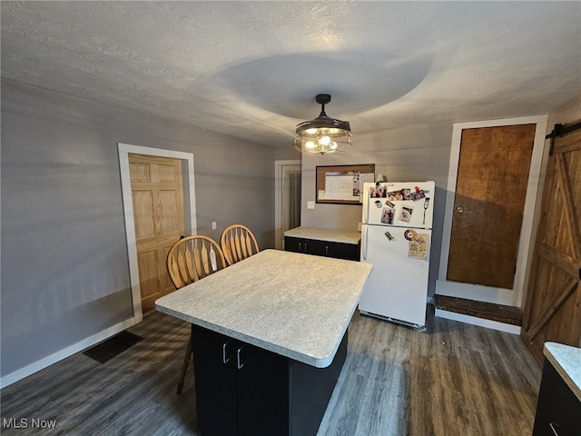 kitchen featuring a center island, a textured ceiling, dark hardwood / wood-style floors, white fridge, and a barn door