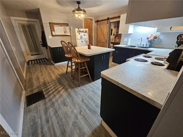 kitchen with a kitchen breakfast bar, a center island, decorative light fixtures, a barn door, and white fridge