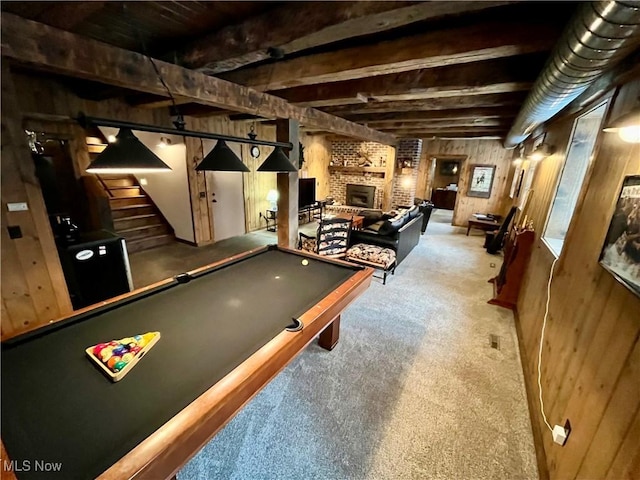 recreation room with beam ceiling, carpet, a brick fireplace, pool table, and wood walls