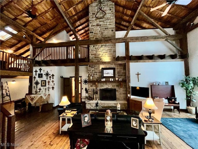 living room featuring high vaulted ceiling, beamed ceiling, hardwood / wood-style flooring, wood ceiling, and ceiling fan