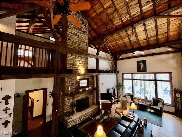 living room with high vaulted ceiling, a brick fireplace, hardwood / wood-style flooring, ceiling fan, and beam ceiling