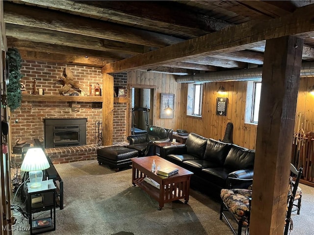 living room featuring beamed ceiling, a brick fireplace, carpet floors, and wooden walls