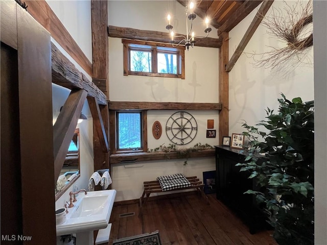 miscellaneous room with an inviting chandelier, sink, dark wood-type flooring, and beamed ceiling