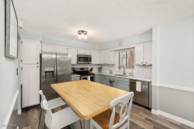 kitchen with stainless steel appliances, sink, white cabinets, and dark hardwood / wood-style flooring