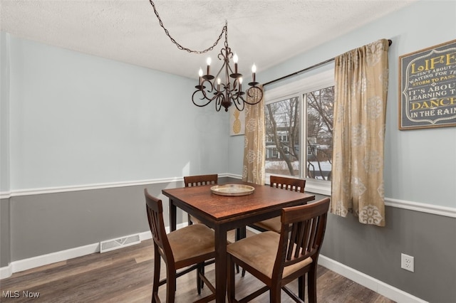 dining room featuring dark hardwood / wood-style floors, an inviting chandelier, and a textured ceiling