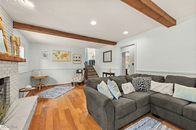 living room featuring a fireplace, beam ceiling, wood-type flooring, and a textured ceiling