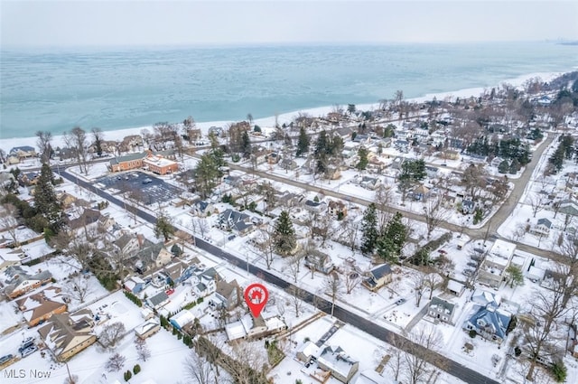 snowy aerial view with a water view and a beach view