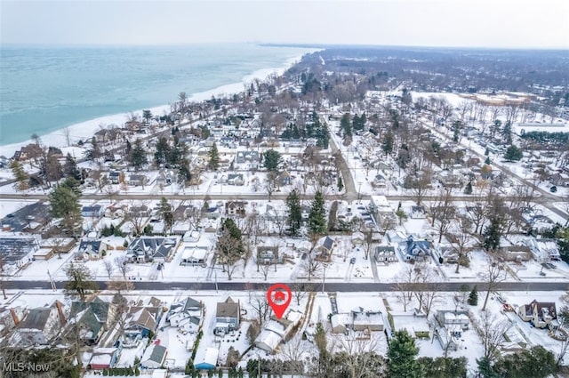 snowy aerial view with a water view and a view of the beach