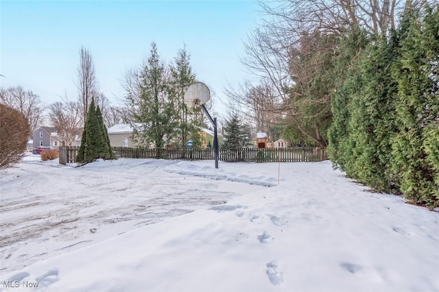 yard layered in snow featuring basketball hoop