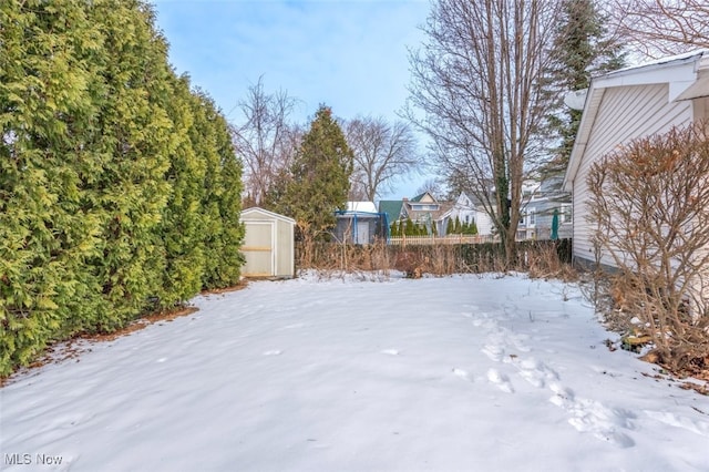 yard layered in snow featuring a shed