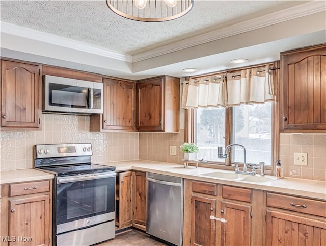 kitchen with sink, decorative backsplash, stainless steel appliances, crown molding, and a textured ceiling