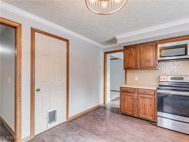 kitchen featuring backsplash, ornamental molding, stainless steel appliances, and light wood-type flooring