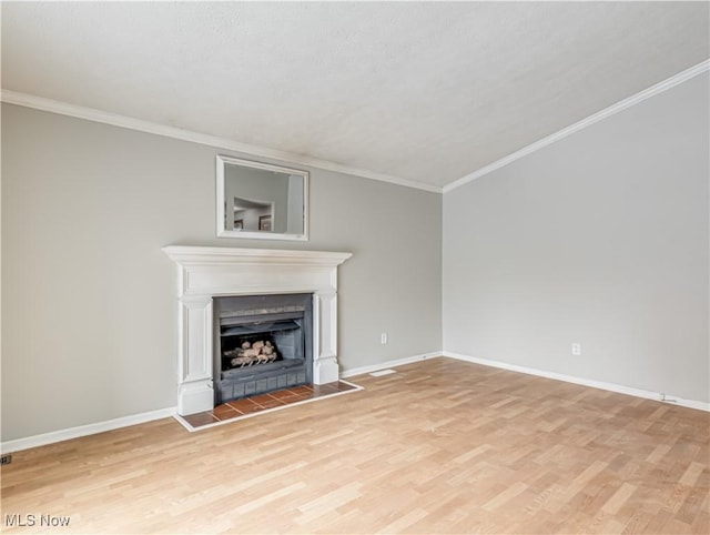 unfurnished living room featuring a tile fireplace, crown molding, and light hardwood / wood-style floors