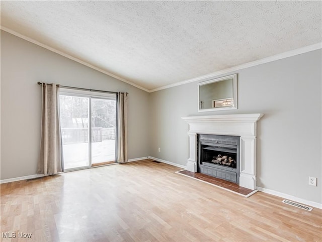 unfurnished living room featuring vaulted ceiling, a fireplace, ornamental molding, a textured ceiling, and light hardwood / wood-style flooring