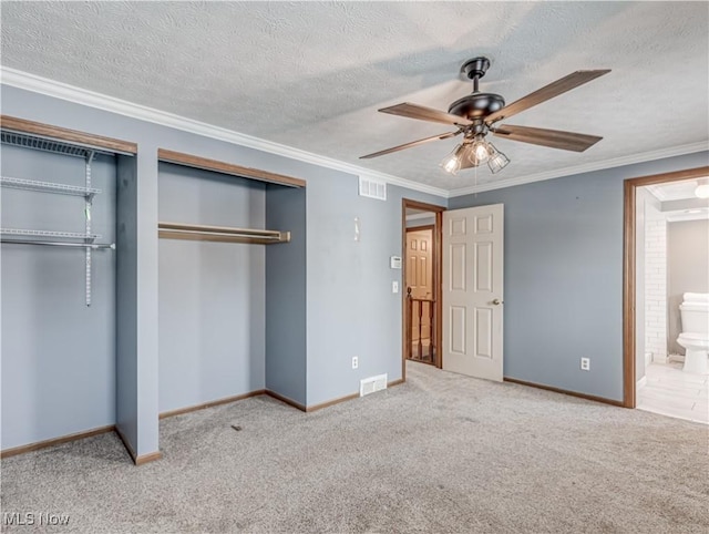 unfurnished bedroom featuring connected bathroom, light colored carpet, ceiling fan, multiple closets, and crown molding