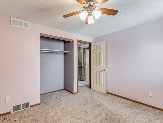 unfurnished bedroom featuring a textured ceiling, light colored carpet, a closet, and ceiling fan