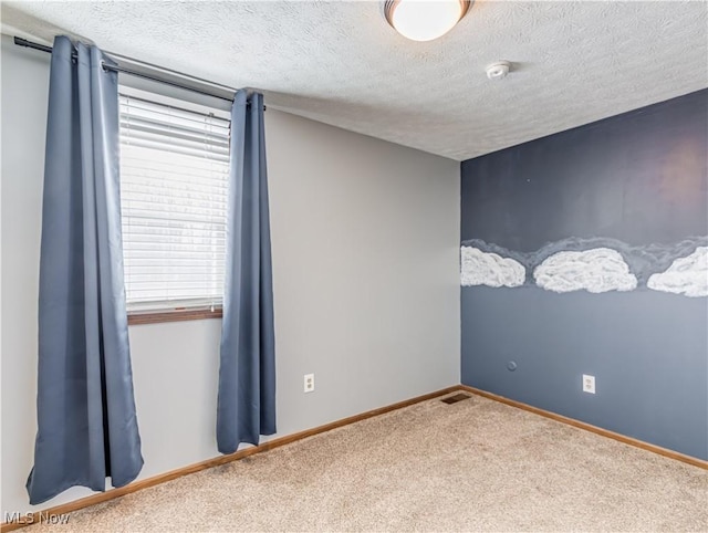 carpeted empty room featuring a textured ceiling