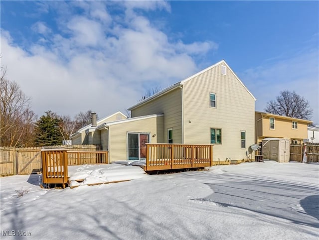 snow covered property featuring a storage unit and a deck