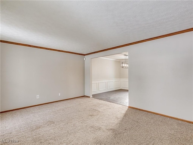 carpeted spare room with crown molding and a textured ceiling