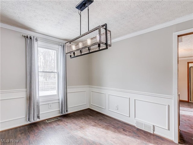 unfurnished dining area with crown molding, dark wood-type flooring, and a textured ceiling