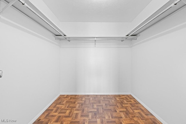 walk in closet with dark parquet flooring