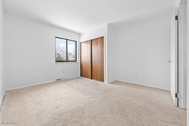 unfurnished bedroom featuring light colored carpet and a closet