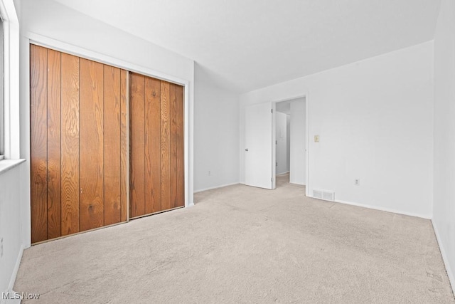 unfurnished bedroom featuring light carpet and a closet