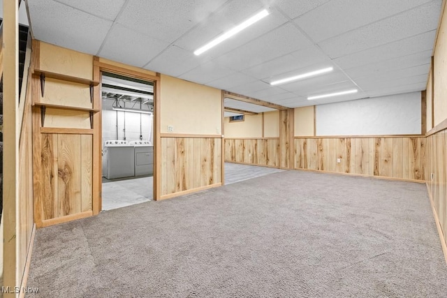 empty room featuring washing machine and clothes dryer, a paneled ceiling, and light colored carpet