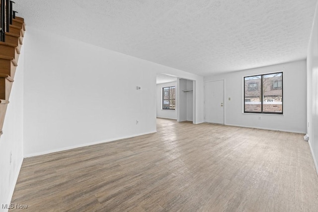 unfurnished living room featuring hardwood / wood-style flooring and a textured ceiling