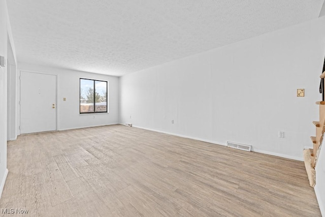 empty room featuring a textured ceiling and light hardwood / wood-style flooring