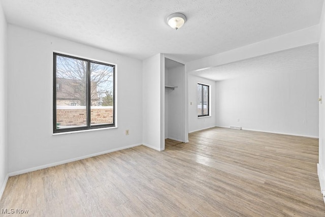 unfurnished room featuring a healthy amount of sunlight, light hardwood / wood-style floors, and a textured ceiling