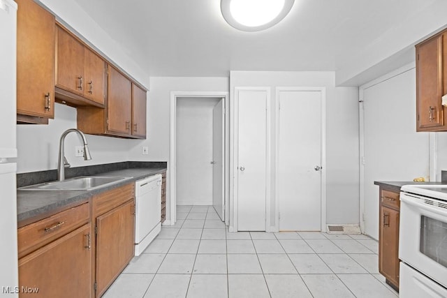 kitchen featuring sink, light tile patterned floors, and white appliances